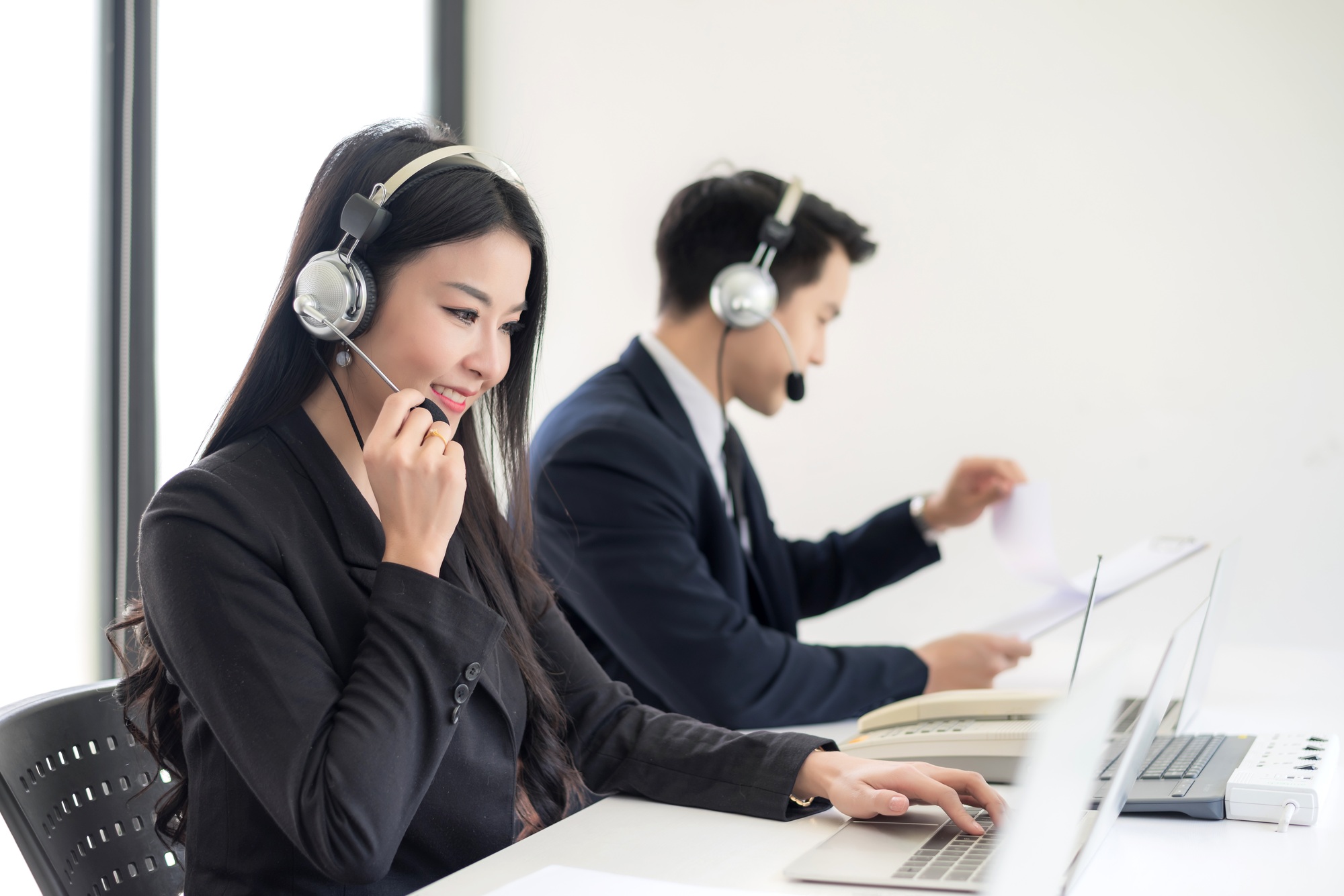 Operator in headphones with microphone consulting client on laptop in customer support service.